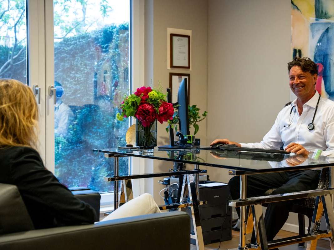 Ärztliches Gespräch zum Check-up am Schreibtisch von Dr. Janssen